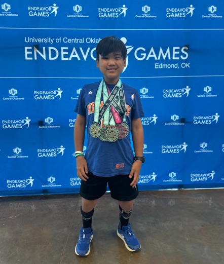 Ryle standing with a full stack of medals at the UCO Endeavor Games