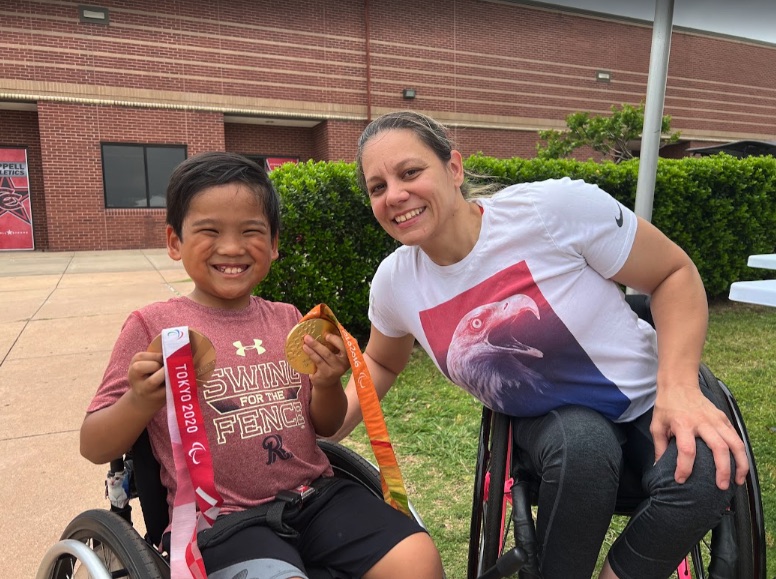 Ryle holding a Tokyo 2020 Paralympic medal beside the athlete who won it