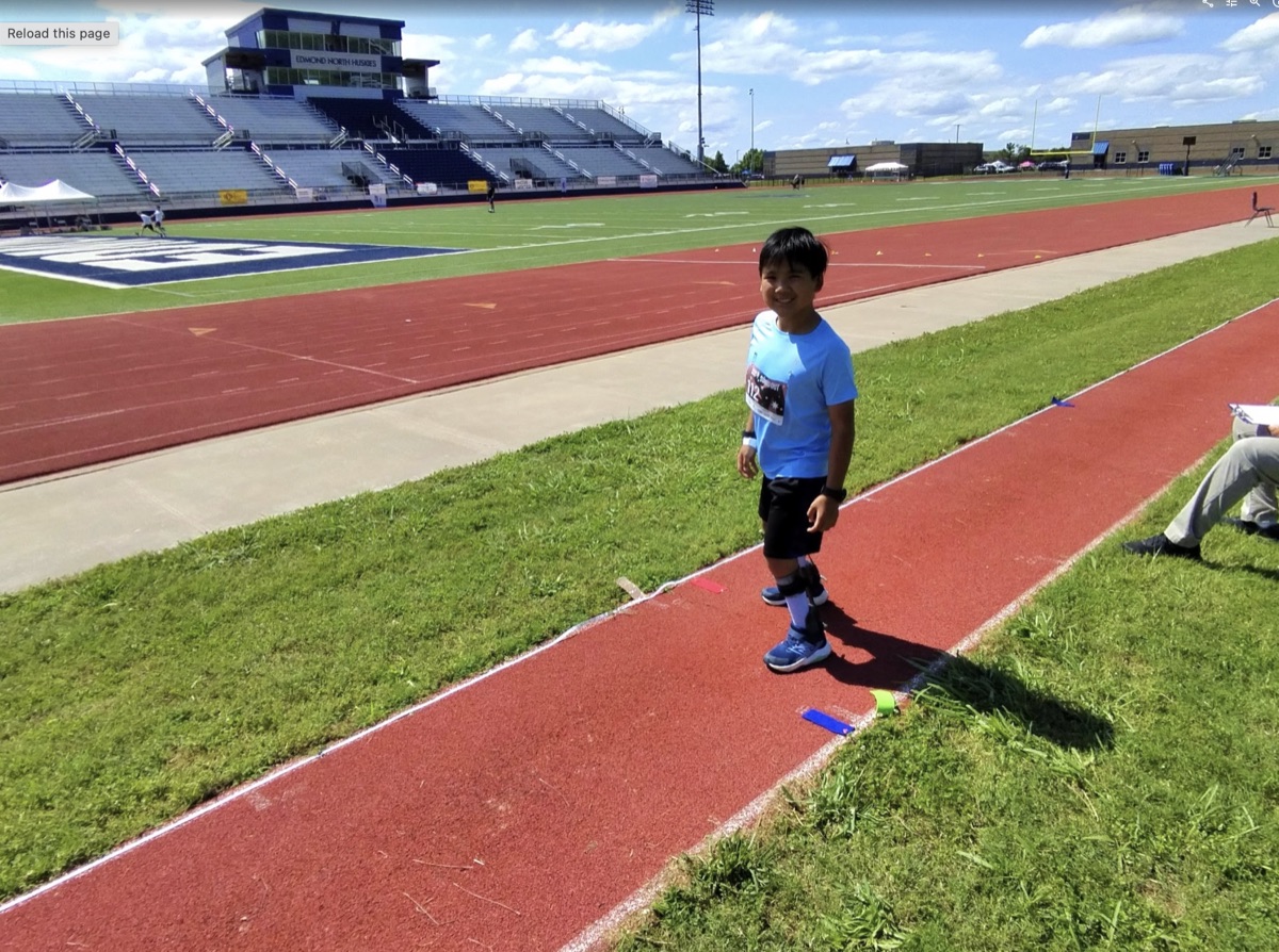 Ryle standing on the track at Endeavor Games with leg braces