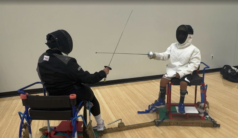 Ryle fencing from a wheelchair frame, en garde against an opponent
